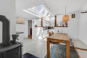 A modern kitchen with skylights, a dining area with a wooden table, and a visible stove.
