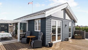 Et moderne hus med terrasse, spiseplads og et flag.