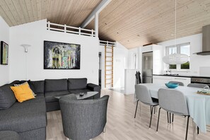 A modern living space with a sofa, dining table, and chairs, a kitchen with a refrigerator, and a wooden ceiling. - Holiday home in Karrebæksminde near the beach (Karrebæksminde)