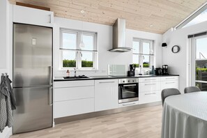 A modern kitchen with white cabinets, stainless steel appliances, and a large window.