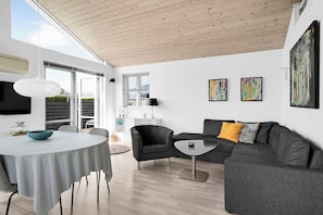 A modern living room with a round table, grey sofa, and artwork on the walls. - Holiday home in Karrebæksminde near the beach (Karrebæksminde)