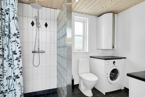 A modern bathroom with a shower, toilet, and washing machine.