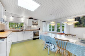 Une cuisine moderne avec des meubles blancs, un îlot central et un coin repas comprenant une table et des chaises.