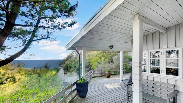 A wooden deck with a bench, a potted plant, and a view of the sea. - Cottage on Fur island with exceptional sea view (Fur)