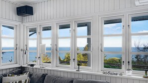 A room with a grey sofa, white walls, and large windows with a view of the sea. - Cottage on Fur island with exceptional sea view (Fur)