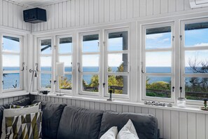 A room with a grey sofa, white walls, and large windows with a view of the sea. - Cottage on Fur island with exceptional sea view (Fur)