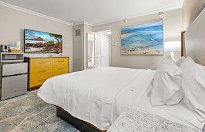 Une chambre d’hôtel avec un lit, une commode, un four à micro-ondes et deux tableaux accrochés au mur.