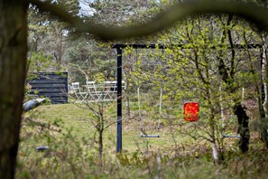 A fenced outdoor area with a metal structure, a wooden shed, and a red object. - Holiday apartment in peaceful surroundings (Nexø)