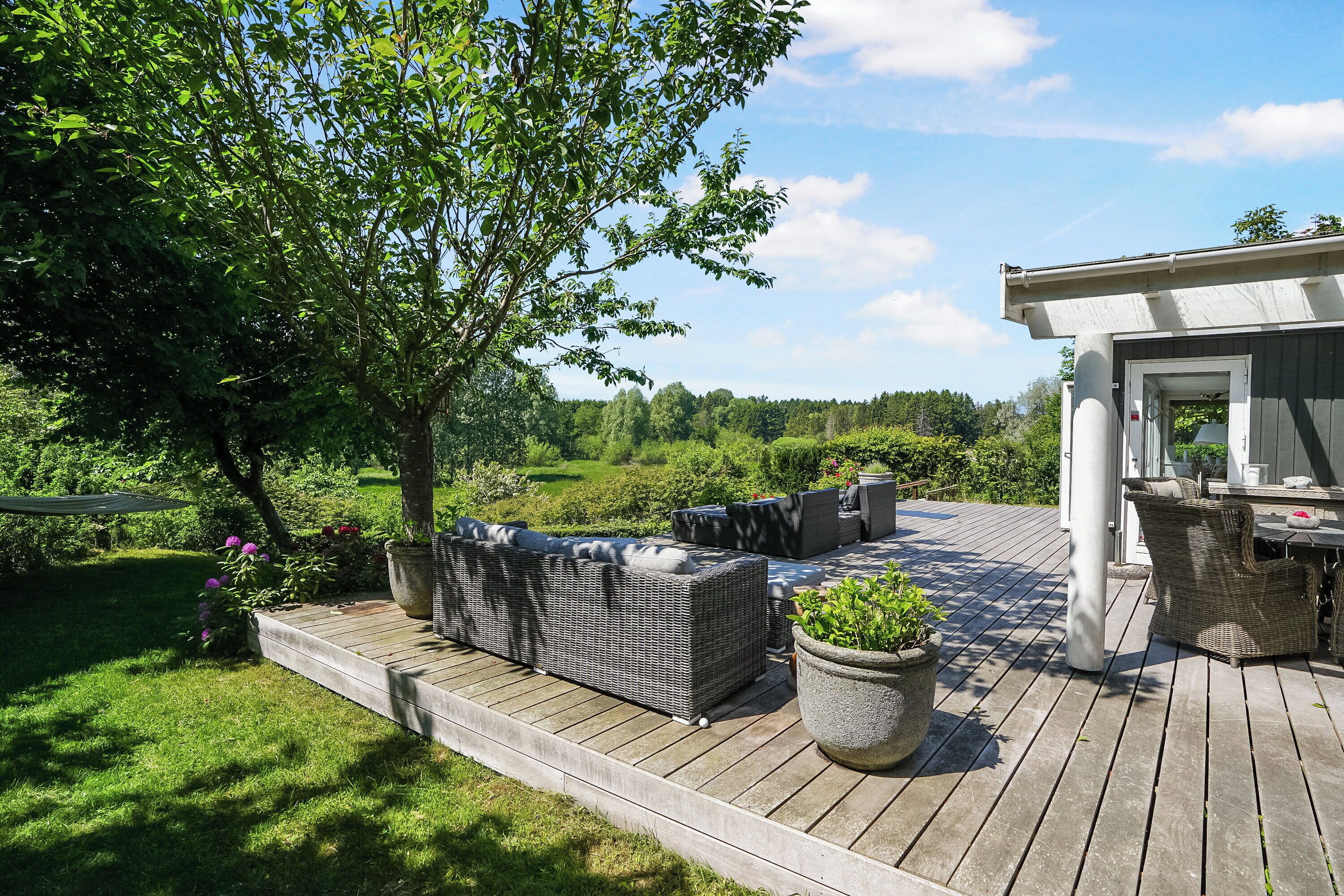 A deck with outdoor furniture, a potted plant, and a building in the background.