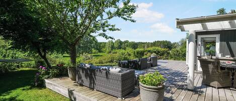 A deck with outdoor furniture, a potted plant, and a building in the background.