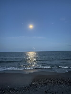 Experience the serene beach at dusk, where gentle waves caress the shore.