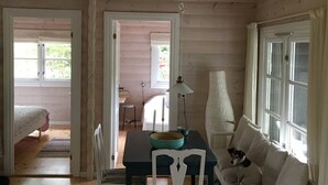 A wooden interior with a dining table, chairs, a sofa, and a lamp. - Log house near a child-friendly sandy beach (Nykøbing Sjælland)
