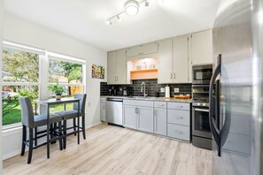 Una cucina moderna con mobili grigi, un piano di lavoro nero e elettrodomestici in acciaio inossidabile.
