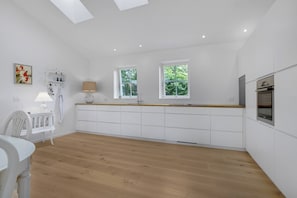 A modern kitchen with white cabinetry, a wooden countertop, and a skylight.