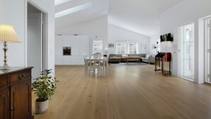 Ett rymligt vardagsrum med ett matbord, stolar, en soffa och ett piano.