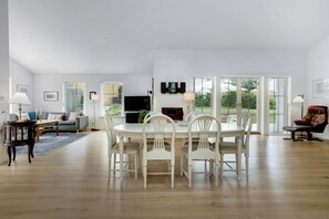 A spacious living area with a dining table, chairs, sofas, and a television. - New and cozy house by the beach and forest (Hornbæk)