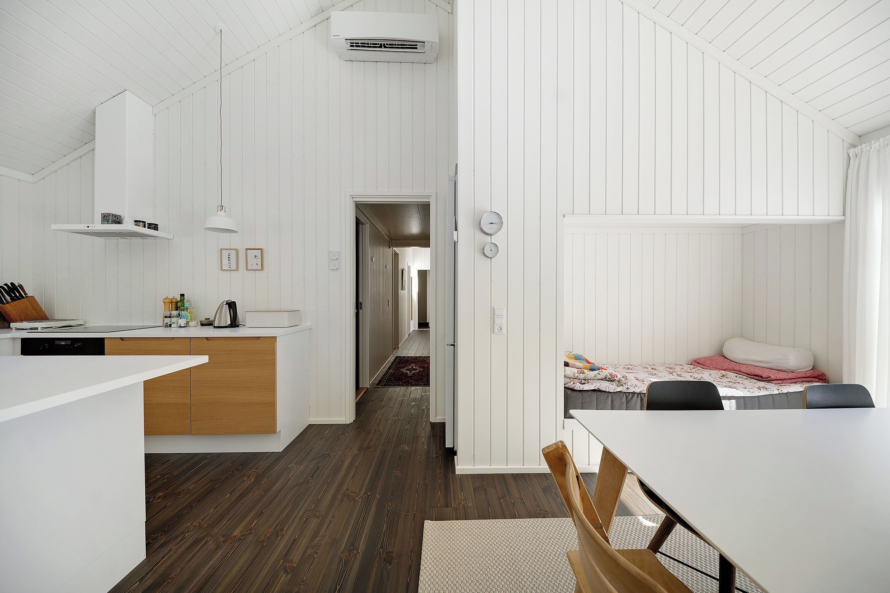 A compact kitchen with white cabinetry, a wooden countertop, and a dining area with a table and chairs.