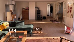 Uma sala de estar com sofá, mesa de centro, lareira, estante e uma porta que dá para outro ambiente.