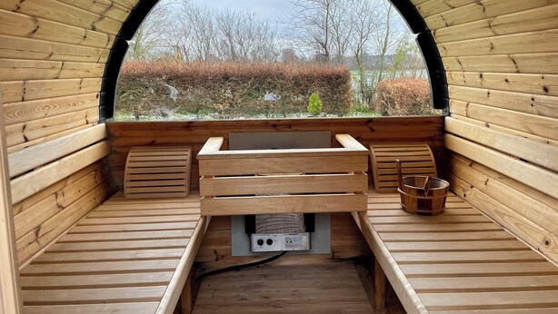 Un interior de madera con un banco, una mesa y una vista a través de un ventanal arqueado.