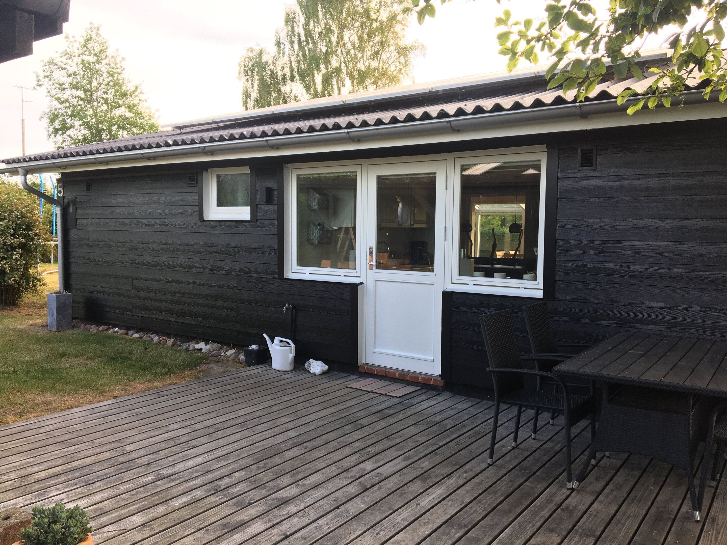 A wooden house with a deck, a door, and windows.