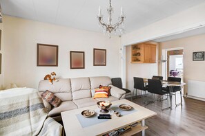 A living room with a sofa, coffee table, and dining area with chairs. - Spacious house with sea views from all rooms (Rønne)