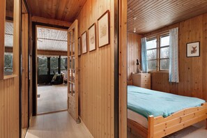 Ein Zimmer mit Holzboden, einem Bett, einem Schminktisch und einem Fenster mit Vorhängen.