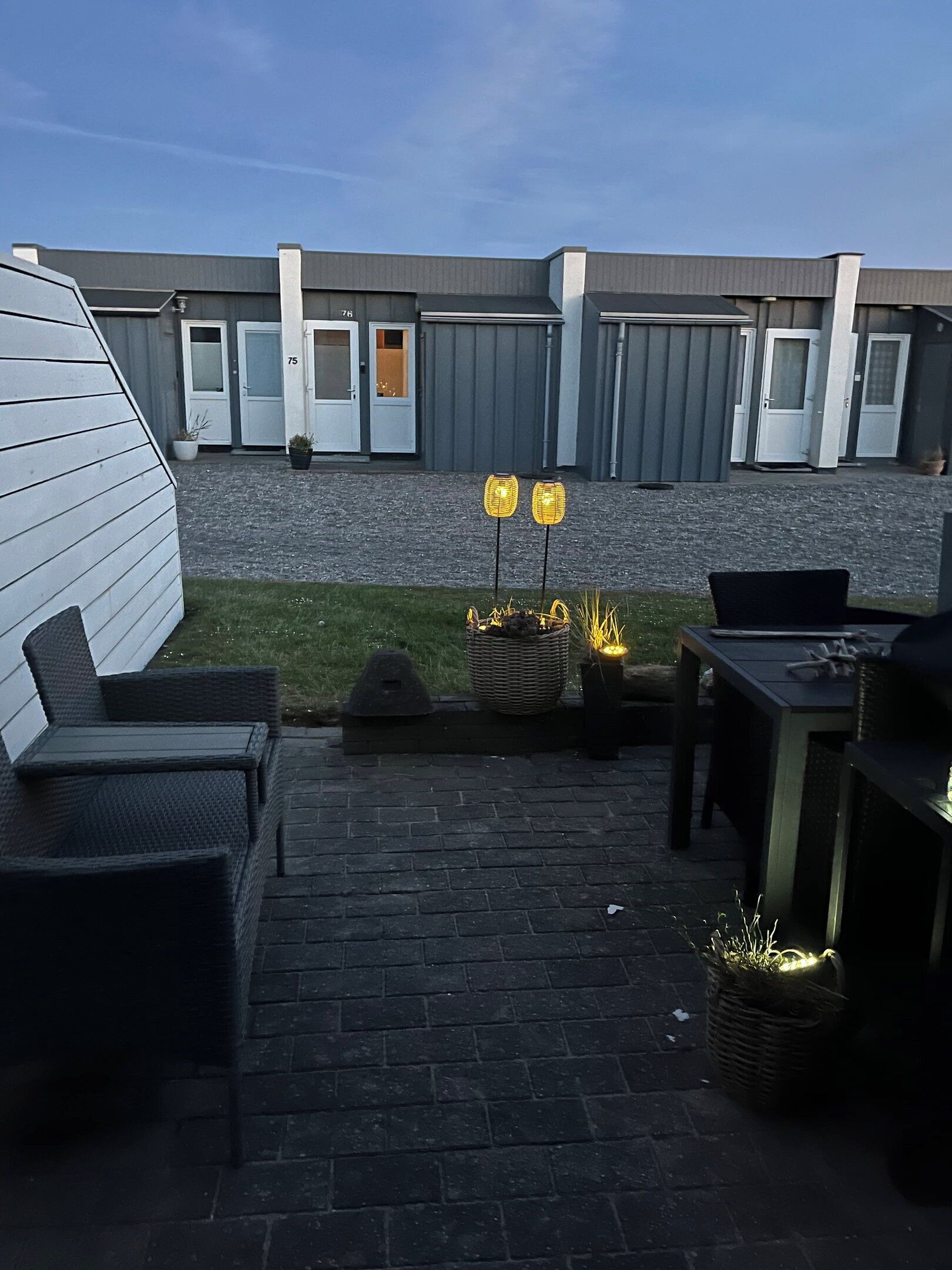 A patio area with outdoor furniture, a fire pit, and a view of a building with numbered doors.