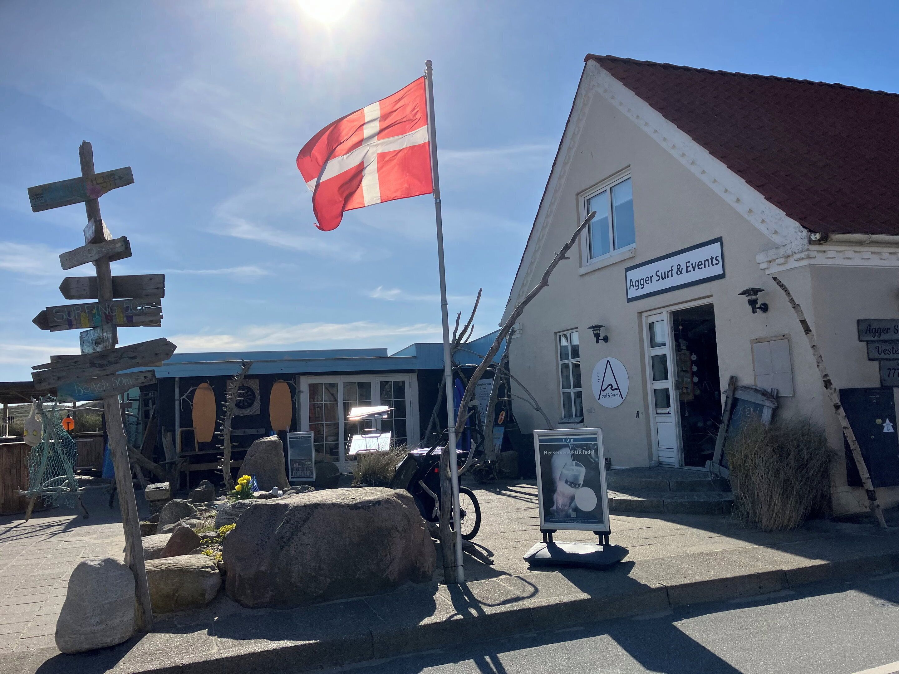 A building with a sign reading 'Agger Surf & Events' and a flagpole with a flag.