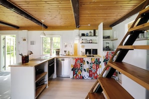 A kitchen with wooden beams, a dishwasher, and a colorful island.
