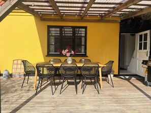 A wooden deck with a table and chairs, a window with a view, and a door leading to an interior space. - Lovely spacious holiday home on Bornholm (Hasle)