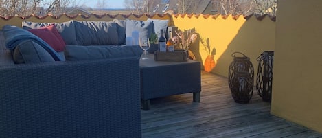 A wooden deck with outdoor furniture, a bottle of wine, and decorative items.
