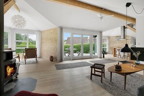 A spacious living area with a fireplace, wooden flooring, and large sliding glass doors leading to an outdoor patio.