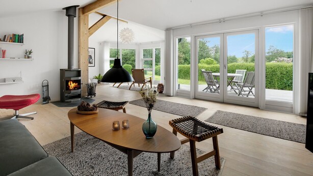 A modern living room with a fireplace, dining area, and large sliding glass doors leading to an outdoor patio.