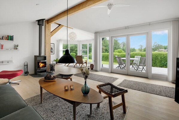 Una sala de estar moderna con chimenea, comedor y grandes puertas correderas de vidrio que dan a un patio exterior.