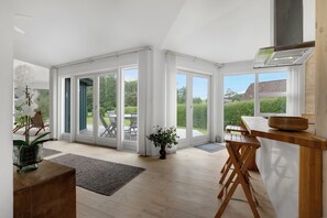 A spacious room with large sliding glass doors, a wooden dining table, and a potted plant.