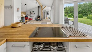 A modern kitchen with a large island, built-in oven, and a view to a deck area.