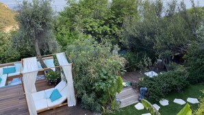 A wooden deck with a white canopy and a white cushioned seating area with teal pillows. - Charming bedroom in luxurious villa with seaview (EZE)