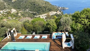 A rooftop pool area with lounge chairs and a view of the sea and hills. - Charming bedroom in luxurious villa with seaview (EZE)