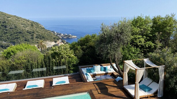 A wooden deck with a pool, lounge chairs, and a canopy bed overlooking a coastal landscape. - Charming bedroom in luxurious villa with seaview (EZE)
