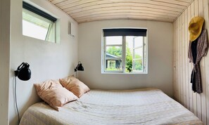 Ein Schlafzimmer mit einem Bett, zwei Nachttischlampen, einem Fenster mit Aussicht und einem Hut an der Wand.