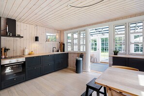 Une cuisine moderne avec des meubles en bois, un four encastré et une grande fenêtre.