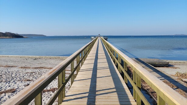 A wooden pier extending into calm water with a clear sky. - Cozy central located townhouse in Nakskov (Nakskov)