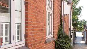 A narrow brick building with large windows and a narrow sidewalk. - Cozy central located townhouse in Nakskov (Nakskov)