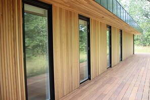 Een modern gebouw met verticale houten lambrisering, grote glazen deuren en een houten terras.