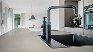 A modern kitchen with a built-in sink, a faucet, and a bottle of hand sanitizer. - Holiday home on Bornholm close to sea and beach (Aakirkeby)