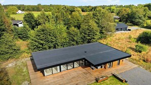 A modern house with a flat roof, large windows, and a wooden deck. - Holiday home on Bornholm close to sea and beach (Aakirkeby)