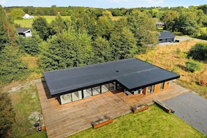 Een modern huis met plat dak, grote ramen en een houten terras.