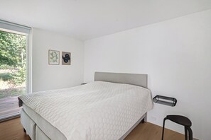 Une chambre à coucher moderne avec un lit, une chaise et une fenêtre.