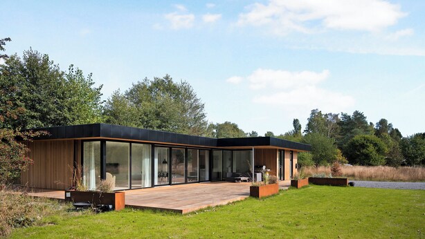 A modern house with large glass windows, a wooden deck, and a grassy yard. - Holiday home on Bornholm close to sea and beach (Aakirkeby)