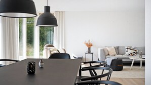 A modern living room with a dining table, chairs, a sofa, and a coffee table. - Holiday home on Bornholm close to sea and beach (Aakirkeby)